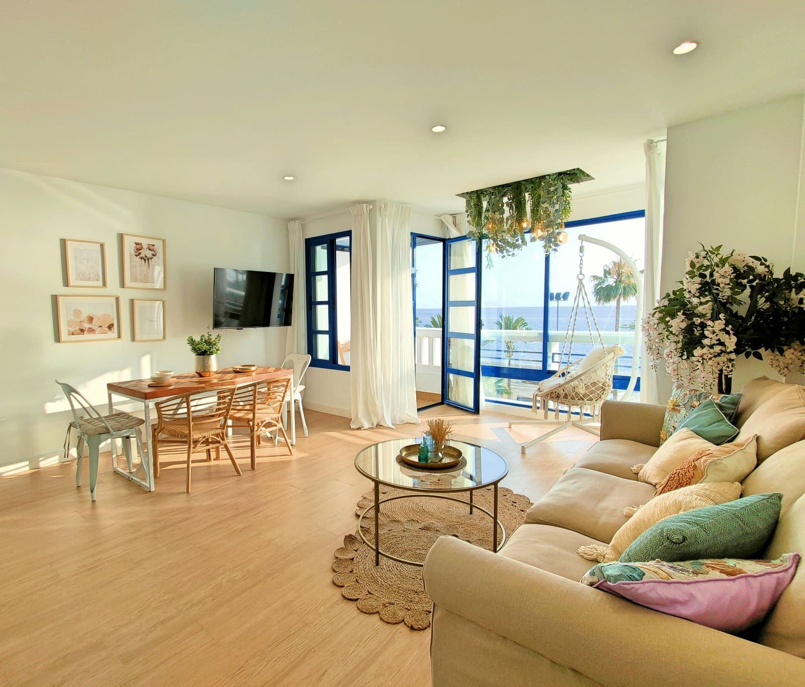 El salón luminoso de un apartamento turístico, con sofá, mesa de comedor y vistas al mar